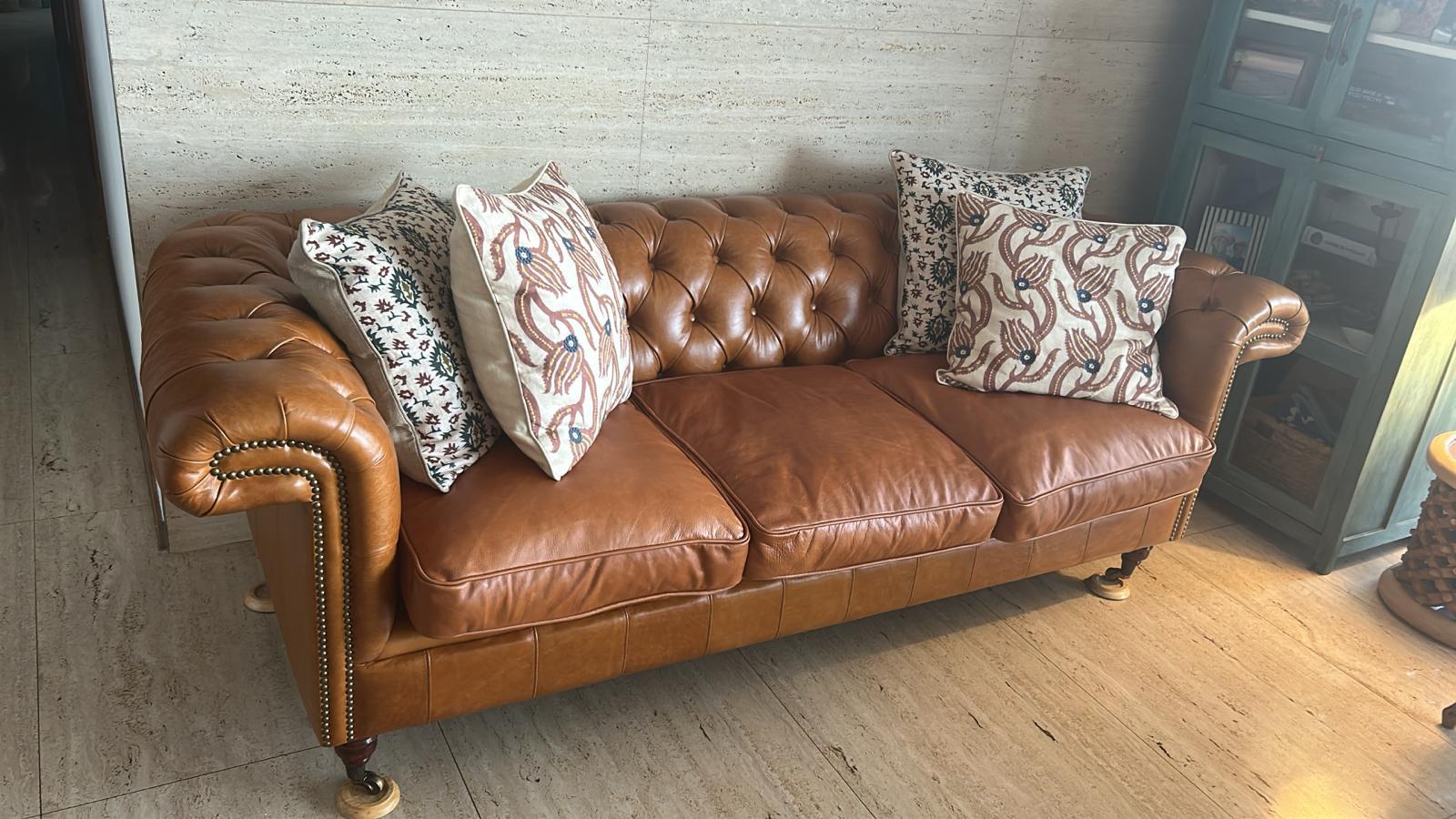 Brown leather tufted Chesterfield 3-seater sofa with decorative pillows