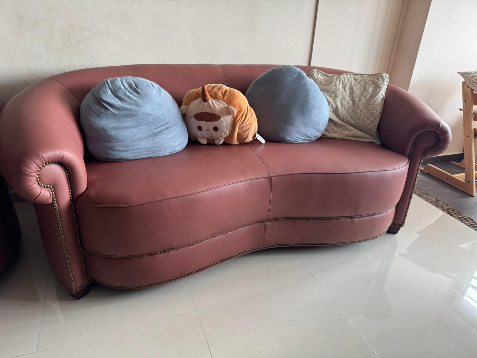 Mauve leather 3-seater sofa with nailhead trim and decorative cushions